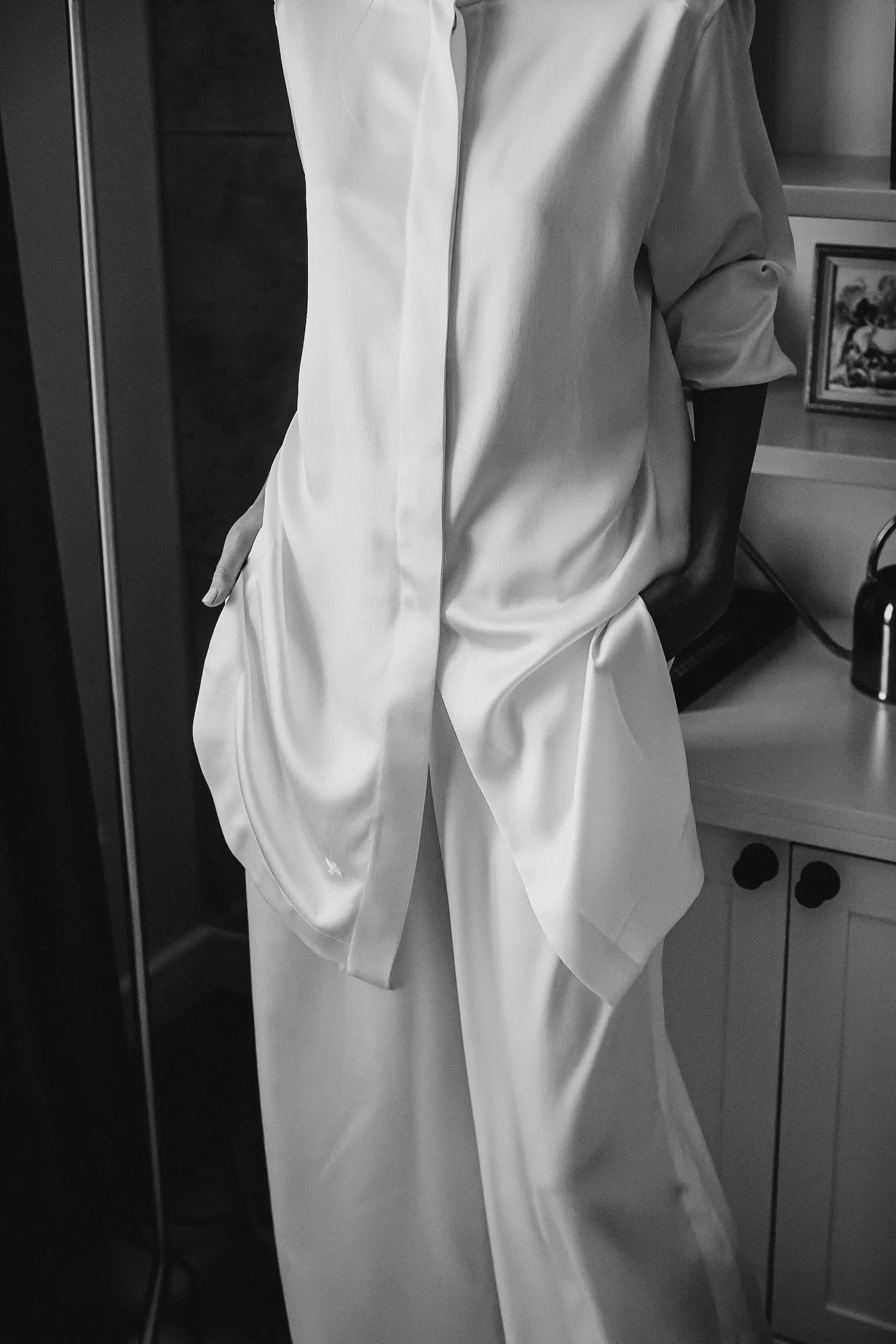 A silk lounge set worn in a home kitchen, shot in black and white.